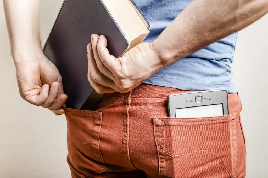 Ebook y libro grande en los bolsillos de un pantalón