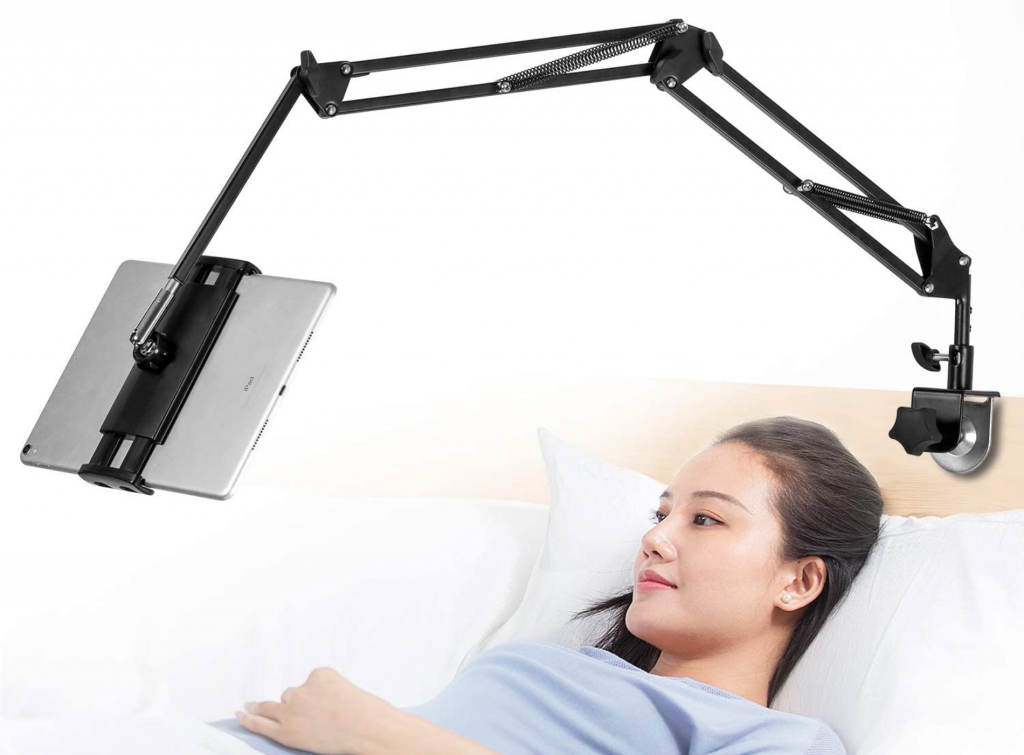 mujer recostada sobre su cama mientras disfruta de contenido en su tablet con soporte de tablets ajustado a la cabecera de la cama