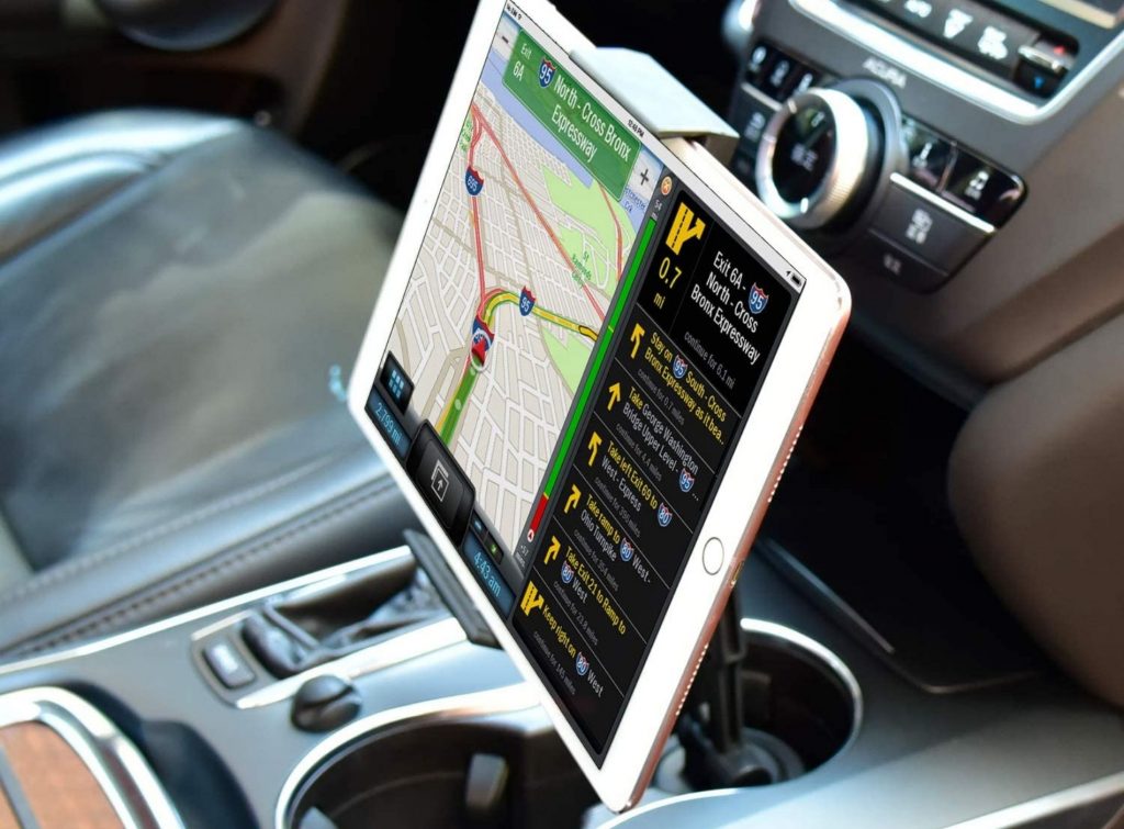 Tablet apoyada sobre soporte para coches ubicado en el posavasos.
