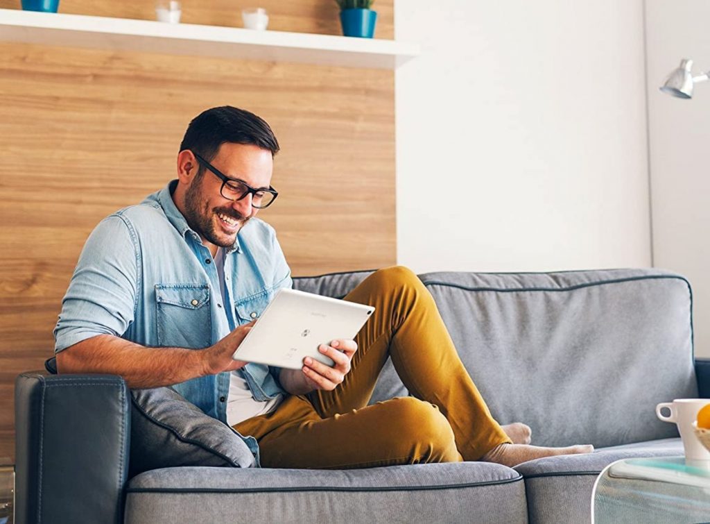 Hombre joven disfrutando sentado en su sala con su tablet SPC Gravity
