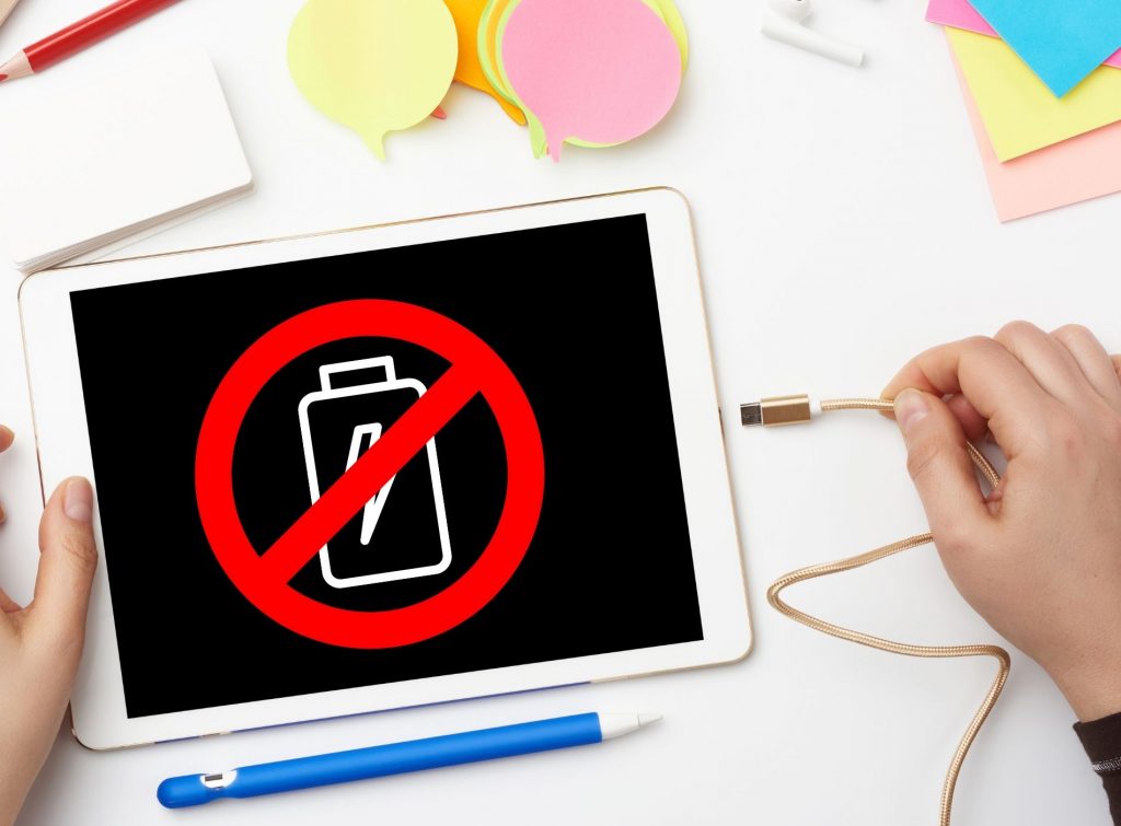 Tablet sin batería a punto de ser conectada al cable cargador
