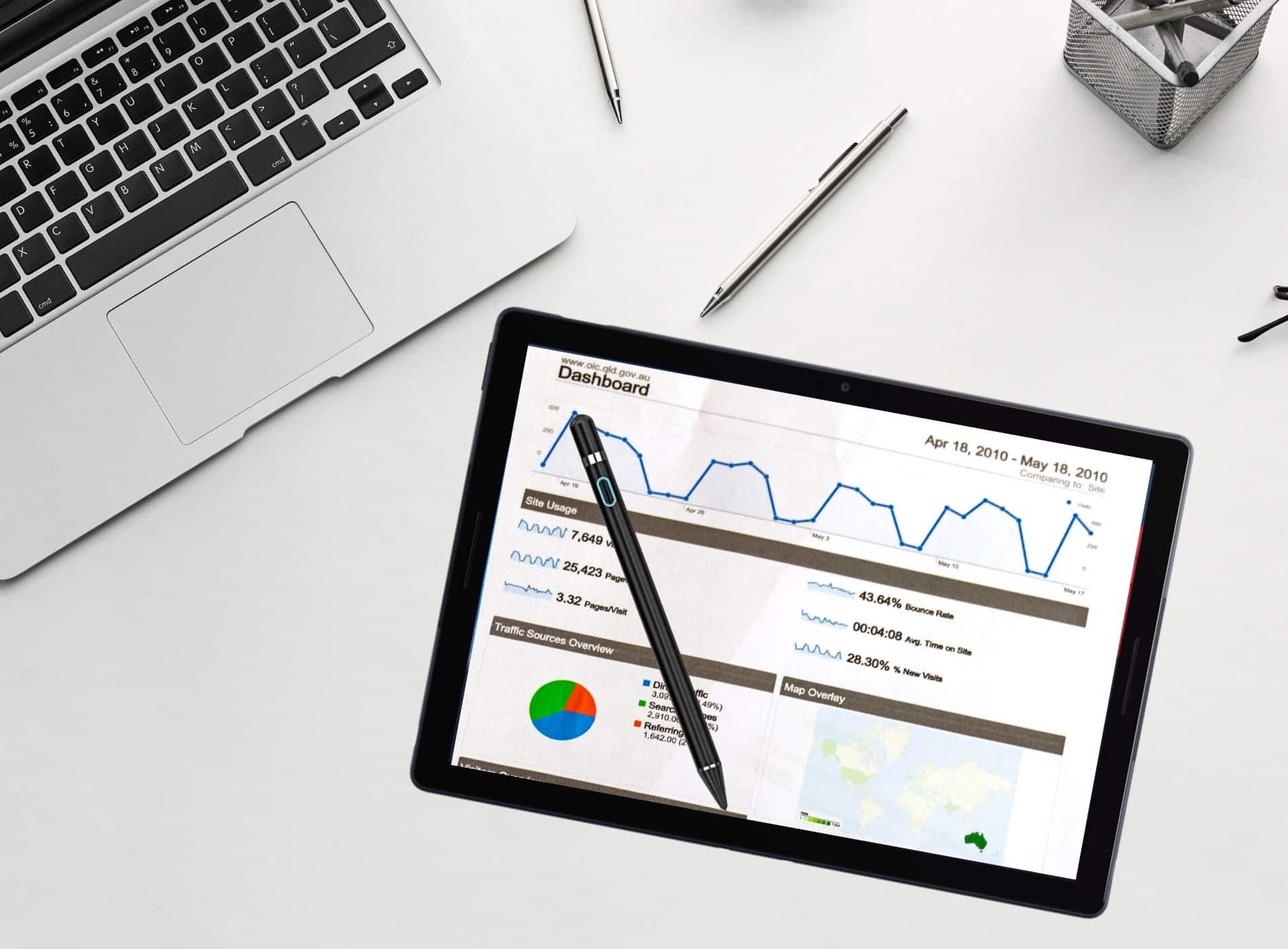 Tablet con lapiz Stylus en escritorio de oficina mostrando graficas de finanzas