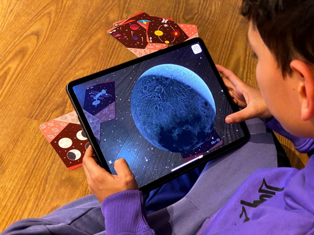 niño utillizando tablet para jugar con planet cards