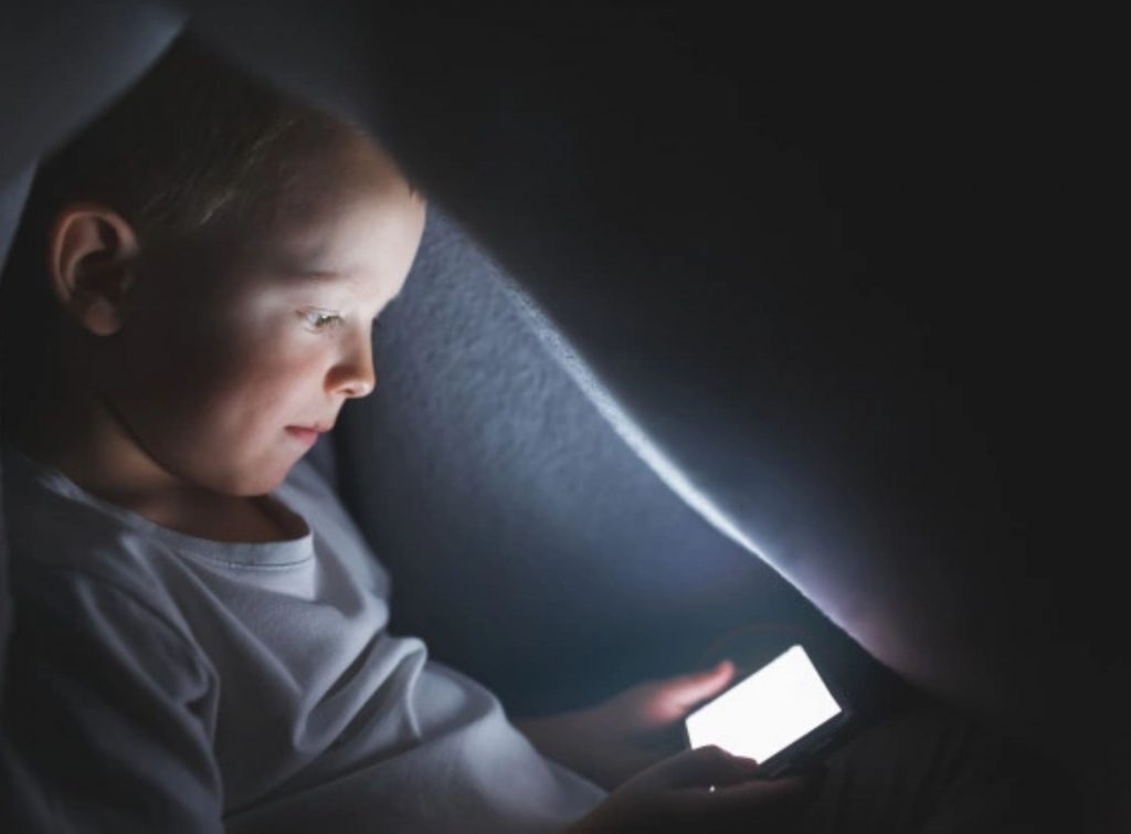 Niño que permanece de noche hasta tarde en su tablet